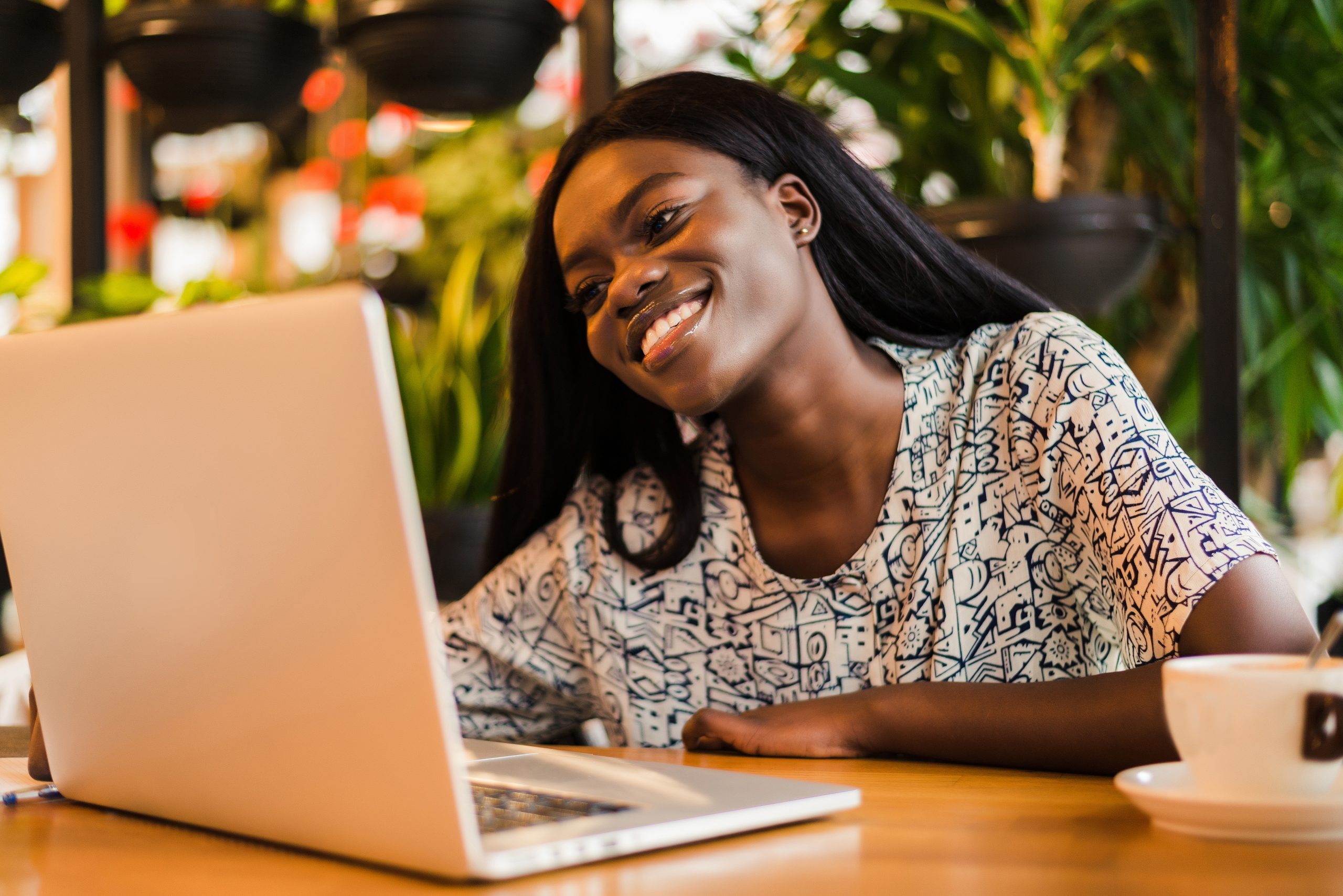Young african woman siting at cafe working on laptop